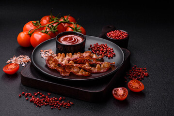 Delicious fresh fried bacon with salt and spices on a dark background