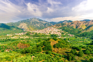 amazing mountain landscape with old yellow italian town among green beatiful mountains and cloudy sky above