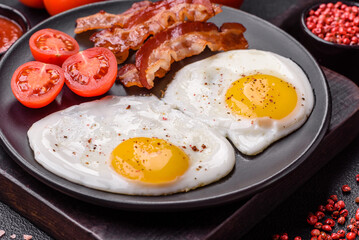 English breakfast with fried eggs, bacon, beans, tomatoes, spices and herbs