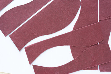 burgundy red paper with rough texture shapes on blank paper