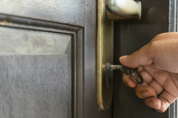 inserting key to door lock to unlock or lock,  wooden door with a wooden door frame, old house