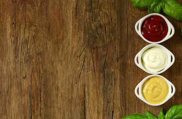 various types of sauce ketchup mayonnaise mustard on wooden background