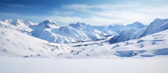 Fototapeta premium A picturesque natural landscape of a snowy mountain range under a blue sky with scattered clouds. The ice caps glisten on the slopes as the wind blows across the horizon