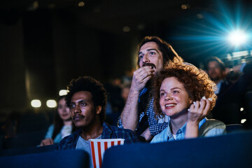 Group of diverse young people watching a movie in cinema with popcorn