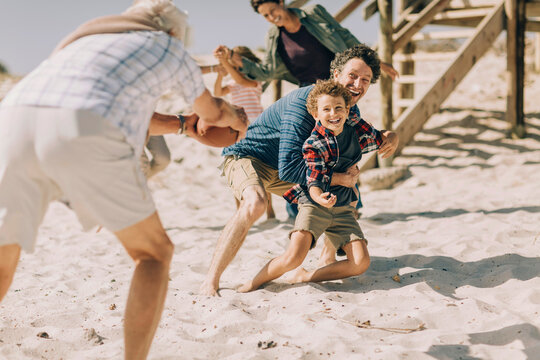 Multigenerational family having fun playing football on the beach