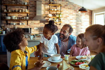 Young mixed family eating together at home - obrazy, fototapety, plakaty