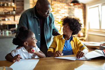 Father helping children with homework at kitchen table