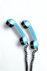 Pair of hanging telephone receivers. Aqua color telephone receivers with a curly wires from the 1970's. Old-fashioned phone from the seventies on a white background. - obrazy, fototapety, plakaty