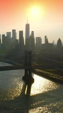 Grey silhouettes of gorgeous New York at sunset. Drone footage slowly approaching the stunning bridges over East River. Pink sky at backdrop. Vertical video