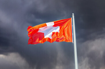 Switzerland national flag waving in the dark cloudy sky