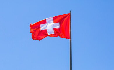 Flag of Switzerland flying in the wind against a blue sky