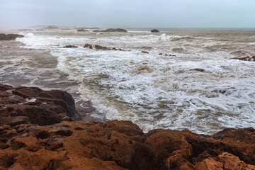 View of the volcanic shore of the stormy Atlantic Ocean in the area of Essaouira in Morocco.