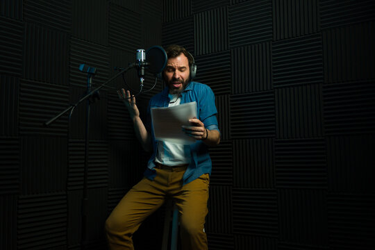 Male voice actor recording in soundproof studio
