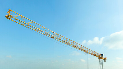 Industrial construction crane with blue sky background at building site - obrazy, fototapety, plakaty