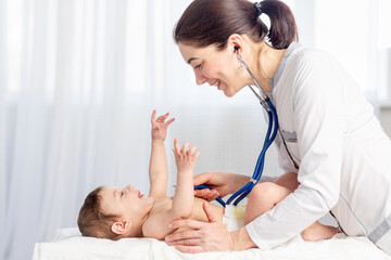 pediatrics, a doctor examines a baby boy and uses a stethoscope to listen to the baby's heartbeat...