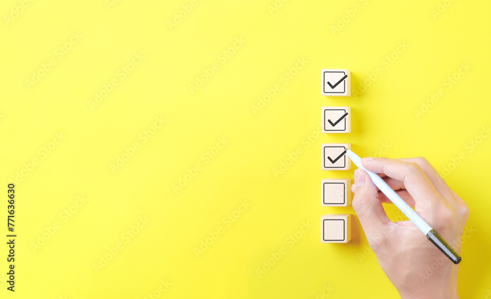 Poster checklist concept. person using a black ink pen to correct sign and tick check mark on wooden block 