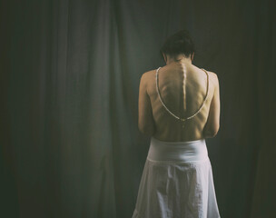 woman seen from behind with a white petticoat-type skirt and a pearl necklace in a romantic attitude II