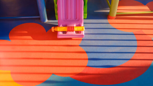 Part of slide and playground equipment on colorful cement floor in kindergarten with light and shadow on surface, high angle view with copy space