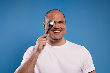man holding a spoon, covering one eye