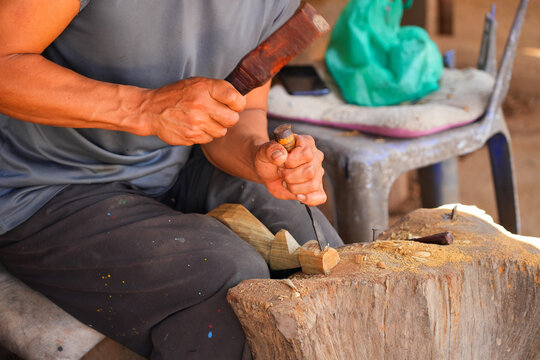 Kayan refugee craftsman chiseling wood to make a small statue in the Huay Pu Keng long-neck village in the Mae Hong Son province in the northwest of Thailand, close to the Burma border
