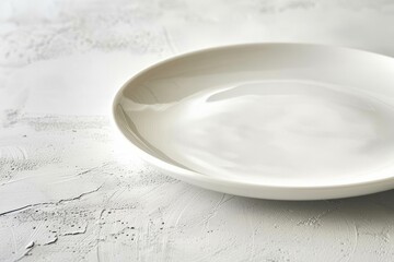 Closeup of an empty white porcelain plate resting on a smooth white table surface - obrazy, fototapety, plakaty
