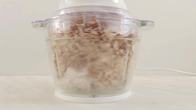 Almonds chopped in electric food chopper in the kitchen. Close-up.
