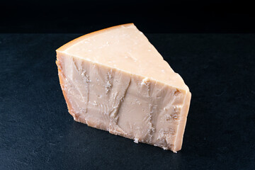 Traditional Parmesan cheese piece as close-up on a black design board with text space