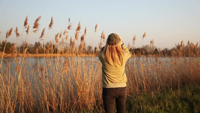 Woman ornithologist or naturalist is watching birds with binoculars. Observation wildlife animals at lake