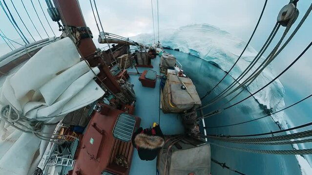 Antarctica explorer. Person walks on the sailing boat anchored near the iceberg in Antarctica. Extremely wide field of view