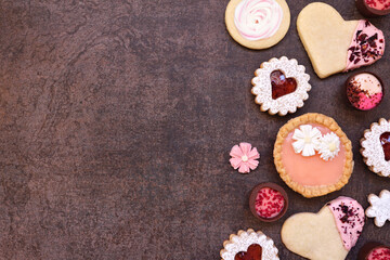 Obraz na płótnie Canvas Mothers Day or love themed baking side border with a variety of cookies and sweet treats. Top view on a dark stone background with copy space.