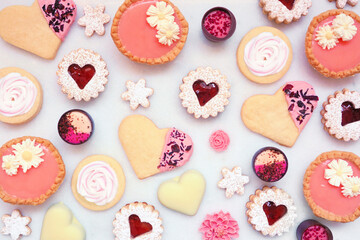 Mothers Day or love themed baking background with assorted cookies and sweet treats. Top view on a white marble background with copy space.