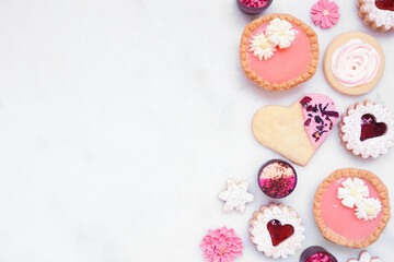 Mothers Day or love themed baking side border with various cookies and sweet treats. Overhead view on a white marble banner background with copy space. - obrazy, fototapety, plakaty