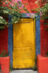 Red building with yellow front door and pink flowers.