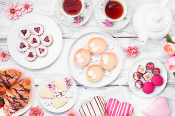 Mother's Day tea table scene over a white wood background. Selection of sweet desserts and pastries.