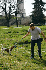 Caucasian man plays toy rope tug-of-war with a dog in Kalemegdan Park in Belgrade. An active spring...