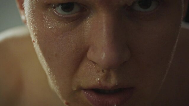 A young man washes himself while in the bathroom he applies water to his face with his hands, pouring cold water over it. Portrait of a man standing in front of a mirror washing his face with water