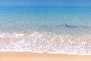 Close up of soft blue ocean wave on clean sandy beach