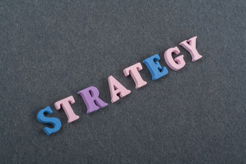 STRATEGY word on black board background composed from colorful abc alphabet block wooden letters, copy space for ad text. Learning english concept.