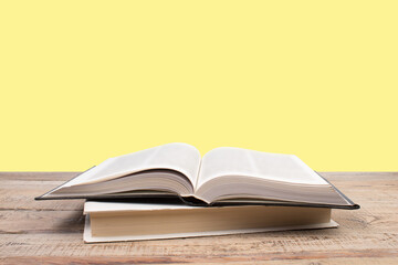 open book. Composition with hardback books, fanned pages on wooden deck table and yellow background. Books stacking. Back to school. Copy Space. Education background.