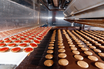 Modern line for bakery cookies with red jam and chocolate. Food industry, biscuit production in factory on conveyor belt
