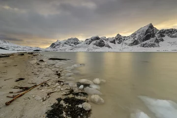 Schilderijen op glas Lofoten Islands in Norway and their beautiful winter scenery at sunset. Idyllic landscape on snow covered beach. Tourist attraction in the arctic circle. Nordic travel destination. © aroxopt