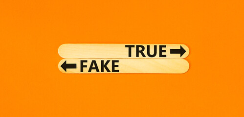 True or fake symbol. Concept word True or Fake on beautiful wooden stick. Beautiful orange table...