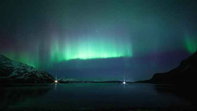 An aurora displaying very rapid motion and intense bright light above a reflective fjord in northern Norway.