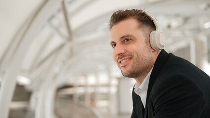 Close up of business man moving his head to music while relaxing listening song from headphones. Caucasian manager wears headset while enjoy listen and move gesture and movement in urban city Urbane. - 771690000
