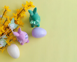 Composition of flowers, bunnies and Easter eggs on a pastel background