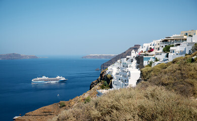 Cruise liner in the sea with a view of the typical white houses of Thira village. Santorini, Cyclades Islands, Greece.
