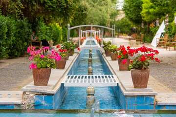 Fototapeta na wymiar Water canals running through a Persian garden and mansion decorating the view of its residents.