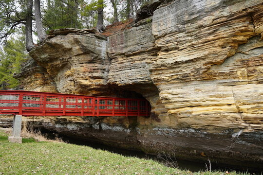 A red man-made bridge leads into a rock tunnel at Pier County Park in Rockbridge, Wisconsin a Native American historical site.