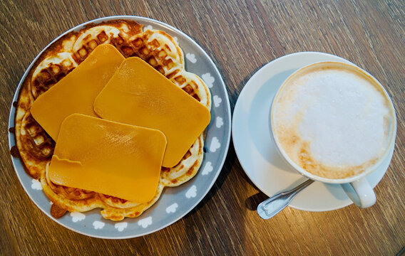 Traditional Norwegian waffles topped with brown cheese, served with coffee.