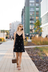 Young woman walking on city streets with while talking on her phone